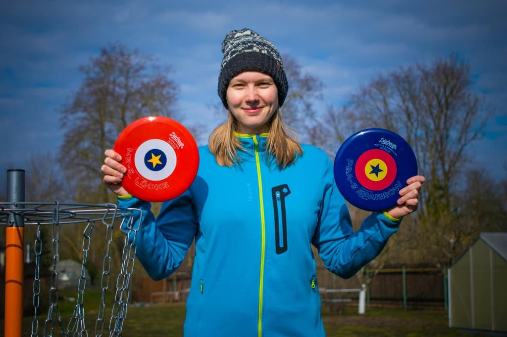 Two disc golf discs next to a basket